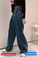 Person wearing high-waisted blue jeans with button details on a plain background