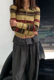 Person wearing a striped sweater and gray pants sitting on a black leather couch.