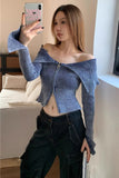 Woman taking a mirror selfie wearing a blue off-shoulder top and dark pants.