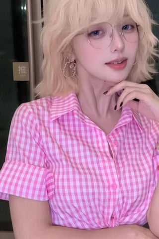 Person wearing a pink and white checkered shirt with a blurred background