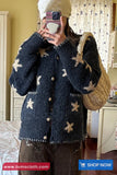 Person wearing a dark blue textured cardigan with star patterns, holding a beige bag indoors.