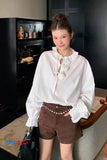 Woman wearing a white blouse and brown shorts in an indoor setting