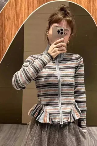 Person wearing a striped jacket taking a mirror selfie.