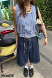 Person wearing a blue checkered top and blue striped pants standing next to a scooter.