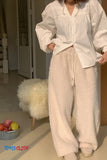 Person wearing a white shirt and beige fluffy pants in a room with a chair and fruit bowl.