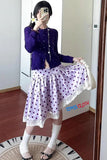 Person wearing a purple cardigan and polka dot skirt in front of a mirror.