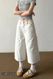 Person wearing a gray crop top and white wide-leg pants with a neutral background