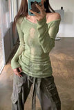 Person wearing a green off-shoulder sweater and gray cargo pants indoors.