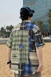 Person wearing a patchwork shirt with a cityscape background