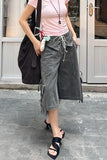 Person wearing a pink top and gray cargo pants with a black bag outdoors.