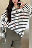 Person wearing a black and white striped shirt with colorful text, holding a silver handbag.