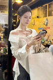 Woman using a phone in a casual setting with a visible brand name on the wall.