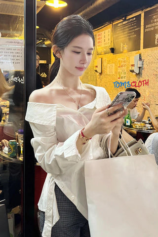 Woman using a phone in a casual setting with a visible brand name on the wall.
