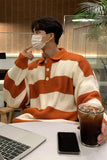Person wearing a striped sweater with a face mask, sitting at a table with a laptop and iced coffee.