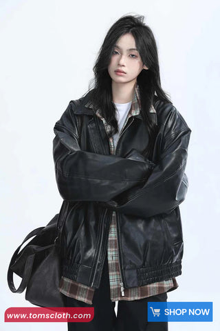 Person wearing a black leather jacket over a plaid shirt on a white background