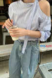 Person wearing a striped shirt and jeans holding a drink, with 'Toms & Cloth' visible.