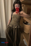 Person wearing a leopard print top and brown pants taking a mirror selfie.