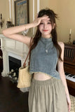 Woman in a denim top and beige pants standing in a room with a fireplace and piano.