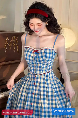 Woman in a blue checkered dress standing next to a piano with a 'Shop Now' button overlay.
