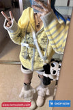 Person wearing a yellow hoodie with gray stripes, white pants, and white boots, holding a phone to take a mirror selfie.