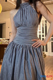 Woman wearing a blue pleated dress indoors.