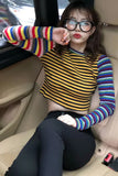 Person wearing a colorful striped shirt sitting inside a vehicle.