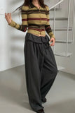 Person wearing a striped sweater and wide-leg pants in an indoor setting