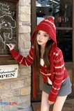Woman wearing a red patterned hoodie standing in front of a store entrance.