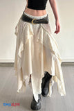 Person wearing a long, flowing beige skirt with a black belt and black boots on a plain background.
