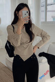 Woman taking a mirror selfie wearing a beige top and black pants in a bright room.