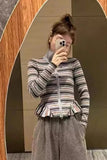 Person wearing a striped jacket and gray pants taking a mirror selfie.