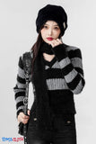 Woman wearing a black and gray striped sweater with a black scarf and hat, holding a black bag on a white background.