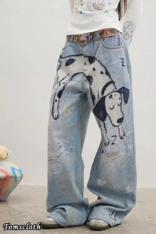 Blue jeans with a dog illustration worn by a person on a plain background