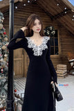 Woman in a black dress with white floral lace standing in front of a wooden cabin decorated for Christmas.