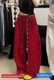 Person wearing red pants with a chain detail in a clothing store.