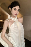 Woman wearing a white dress with a decorative neckline in an indoor setting