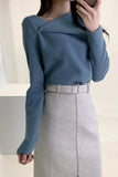 Person wearing a blue sweater and gray skirt against a neutral background