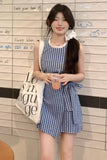 Woman in a blue checkered dress holding a white bag with text, standing against a tiled wall.