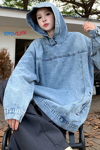 Person wearing a large denim poncho outdoors with 'TOMS CLOTH' branding.