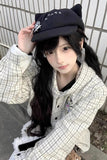 Person wearing a black cap with cat ears and a checkered jacket.