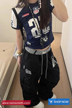 Person wearing a navy blue sports outfit with white accents, standing indoors.