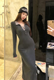 Woman in a gray dress taking a mirror selfie in a bathroom.