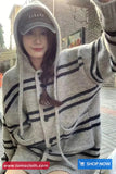 Person wearing a striped hoodie with a visible brand logo, standing outdoors.