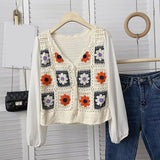 Crocheted vest with floral patterns on a hanger against a white background