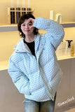 Person wearing a light blue checkered puffer jacket in an indoor setting