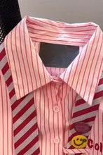 Pink striped shirt with a red and white striped tie and a smiley face design on a black background