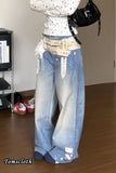 Person wearing a patterned top and blue jeans in an indoor setting with shoes and a TV in the background.