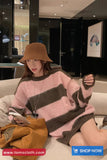 Person wearing a pink and brown striped sweater and brown hat sitting on a couch.