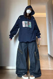 Person wearing a navy hoodie with text and graphics, paired with dark jeans indoors.