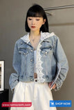 Woman wearing a denim jacket with lace details against a plain background